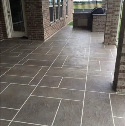 Covered patio in Brandon, FL with a large-format stone-tile stamped concrete floor beside a brick outdoor kitchen